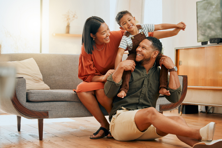 A happy mixed race family of three relaxing in the lounge and being playful together. Loving black family bonding with their son while playing fun games on the sofa at home