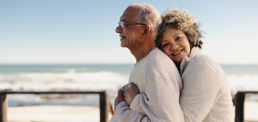Elderly Couple enjoys the senior benefits of life insurance offered by Final Expense plan as they hold hands on a beach.